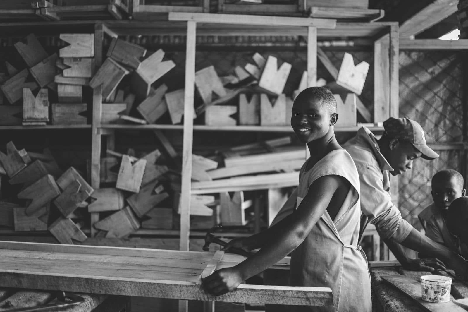 Jeunes apprentis en atelier de menuiserie travaillant une planche de bois, photo en noir et blanc