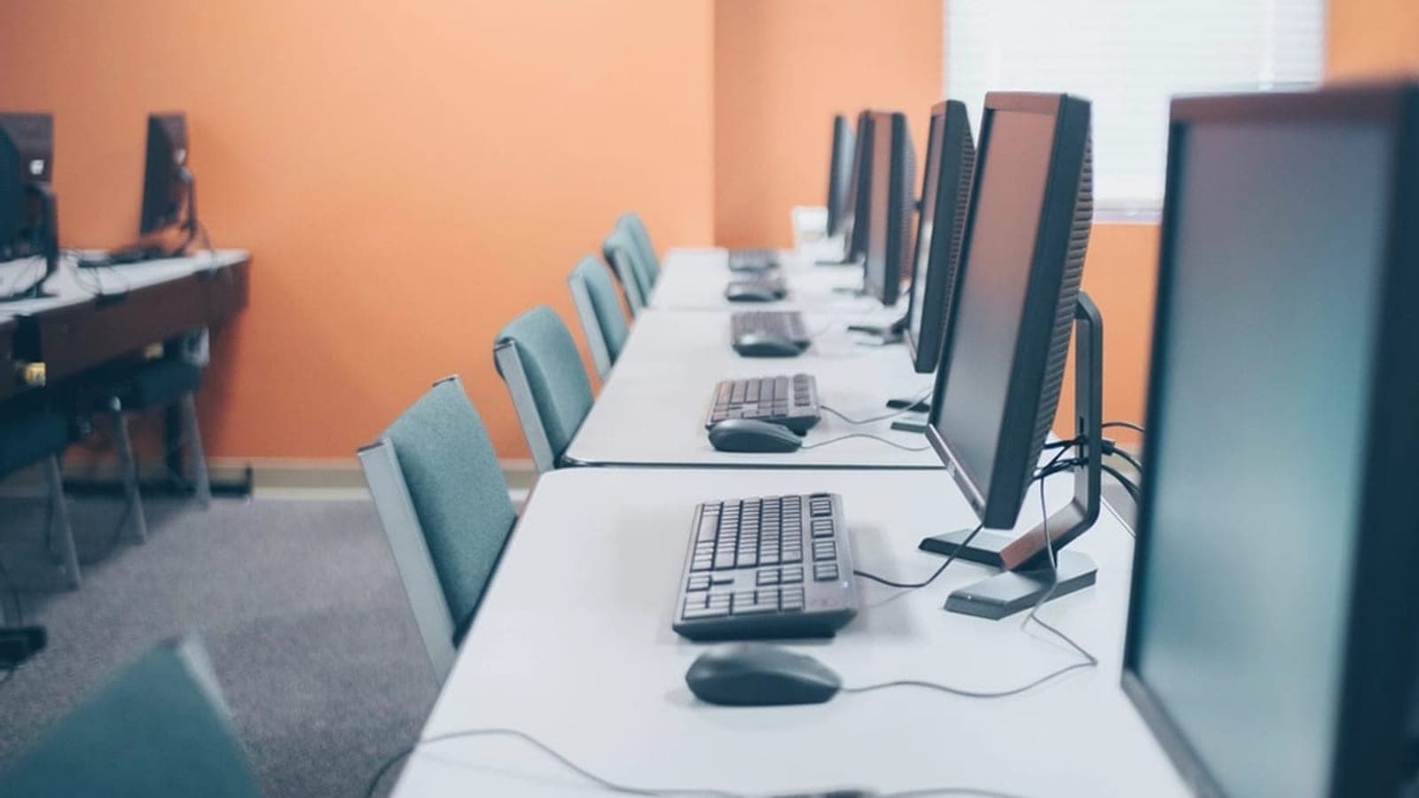 Une étudiante compare deux brochures de centres de formation devant un ordinateur portable