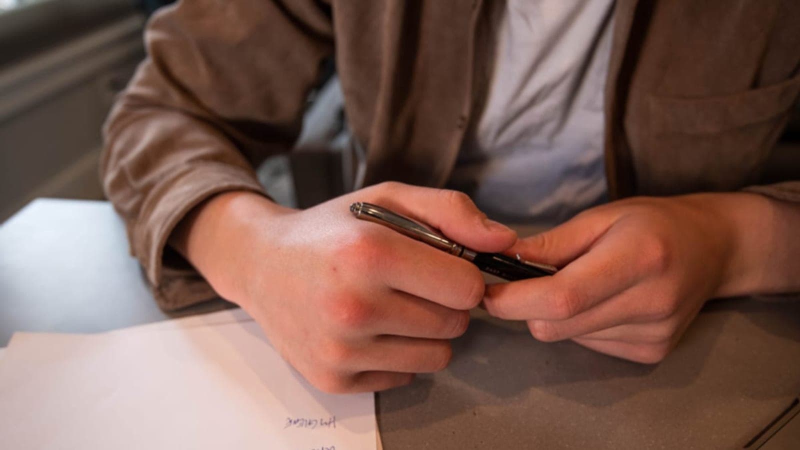 Un jeune alternant remplit sa déclaration de revenus en ligne sur un ordinateur portable, ses bulletins de salaire posés à côté