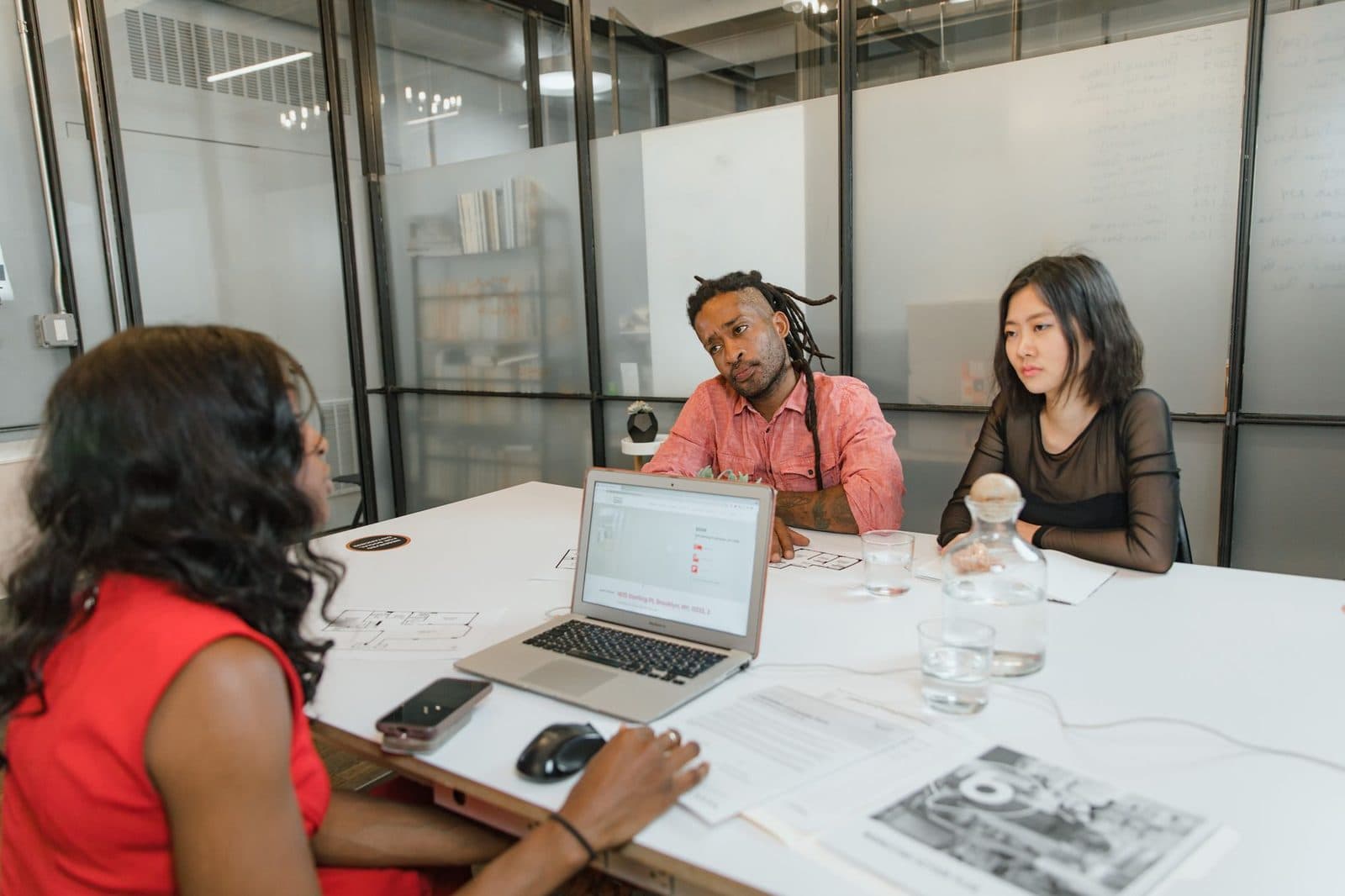 Trois jeunes professionnels en réunion autour d'une table de bureau avec ordinateur portable et documents