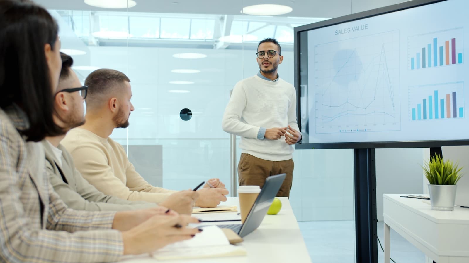 Un professionnel présente des graphiques et des statistiques à des collègues lors d'une réunion