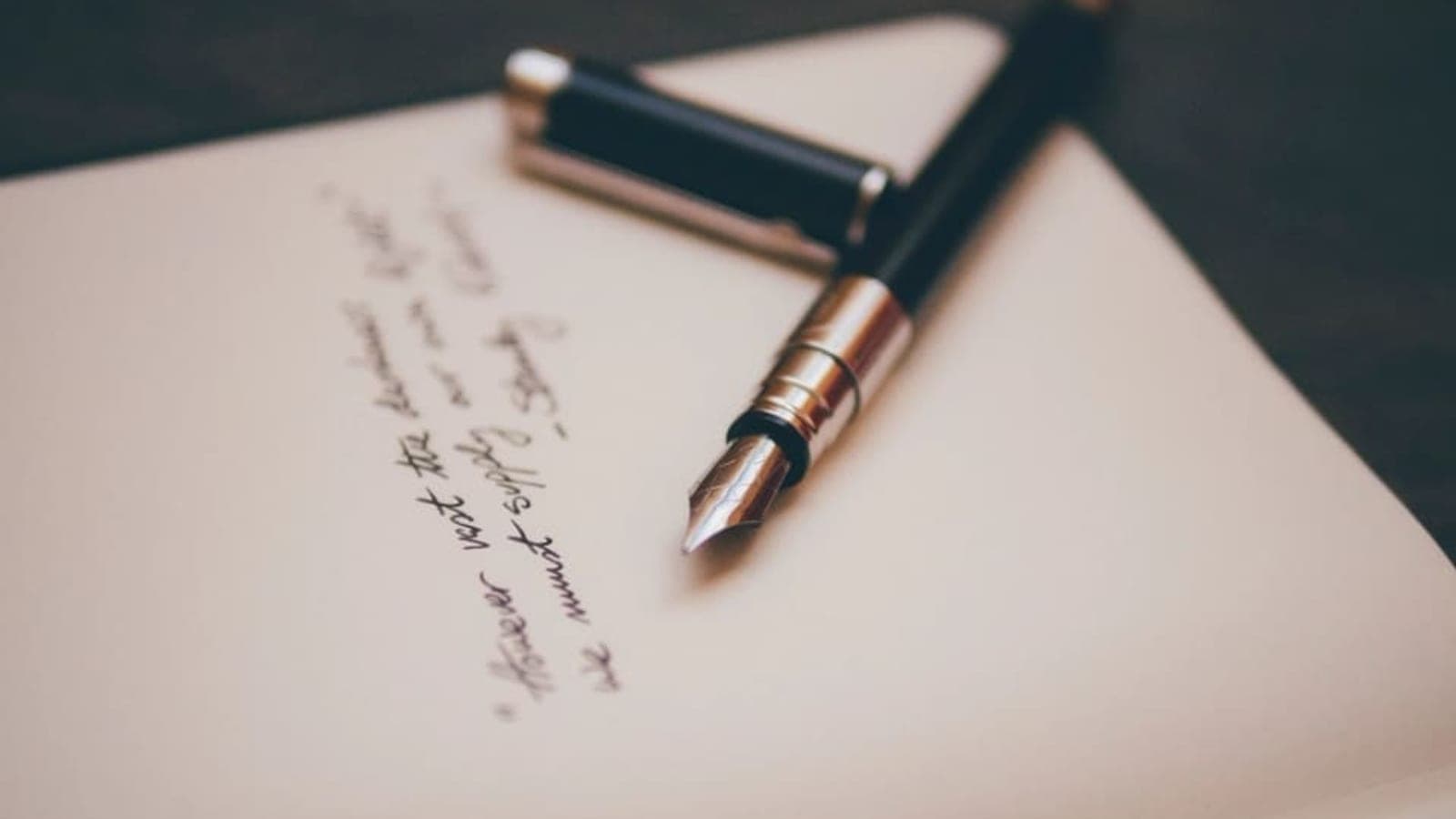 Un stylo-plume ouvert posé sur une feuille couverte d'une écriture manuscrite
