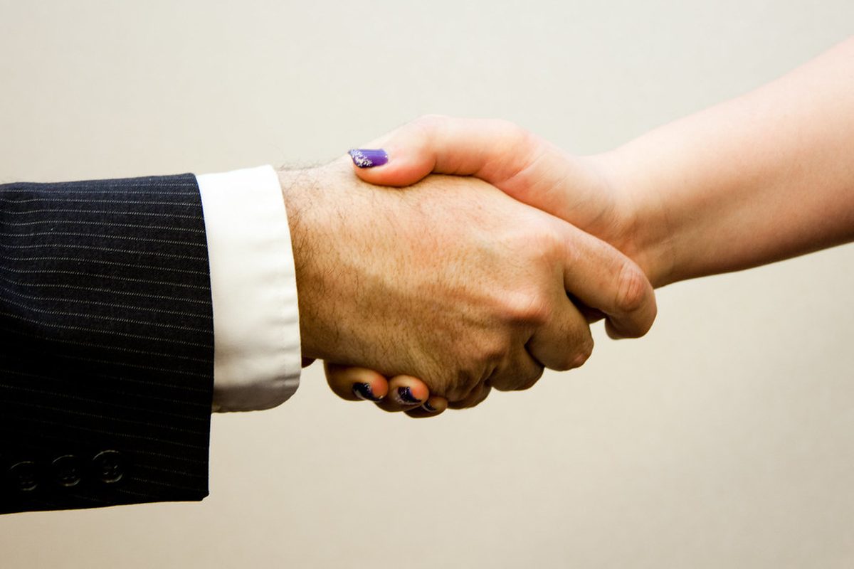Un recruteur et un jeune candidat se serrent la main après la signature d'un contrat d'apprentissage
