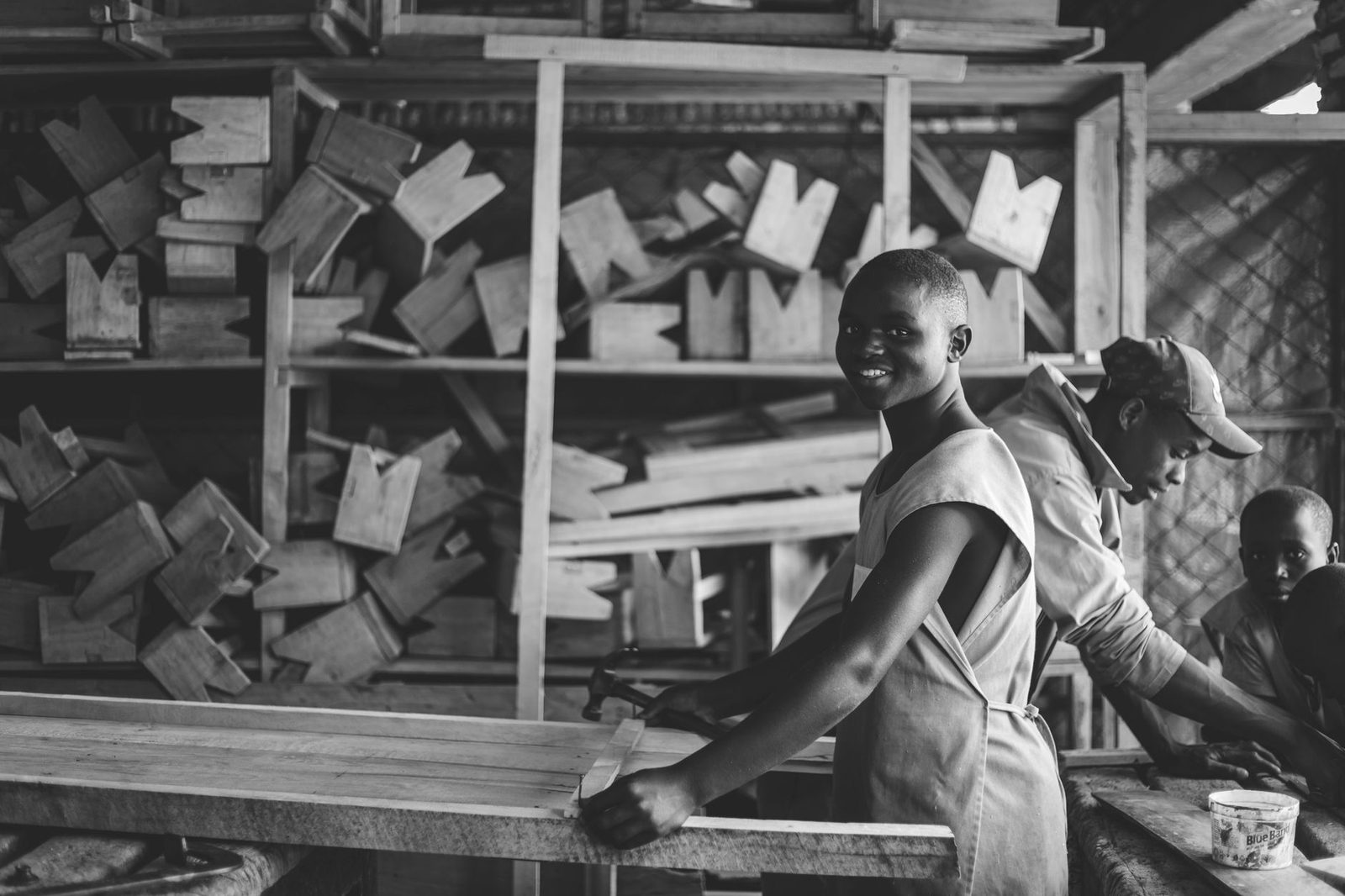 Jeunes apprentis en atelier de menuiserie travaillant une planche de bois, photo en noir et blanc