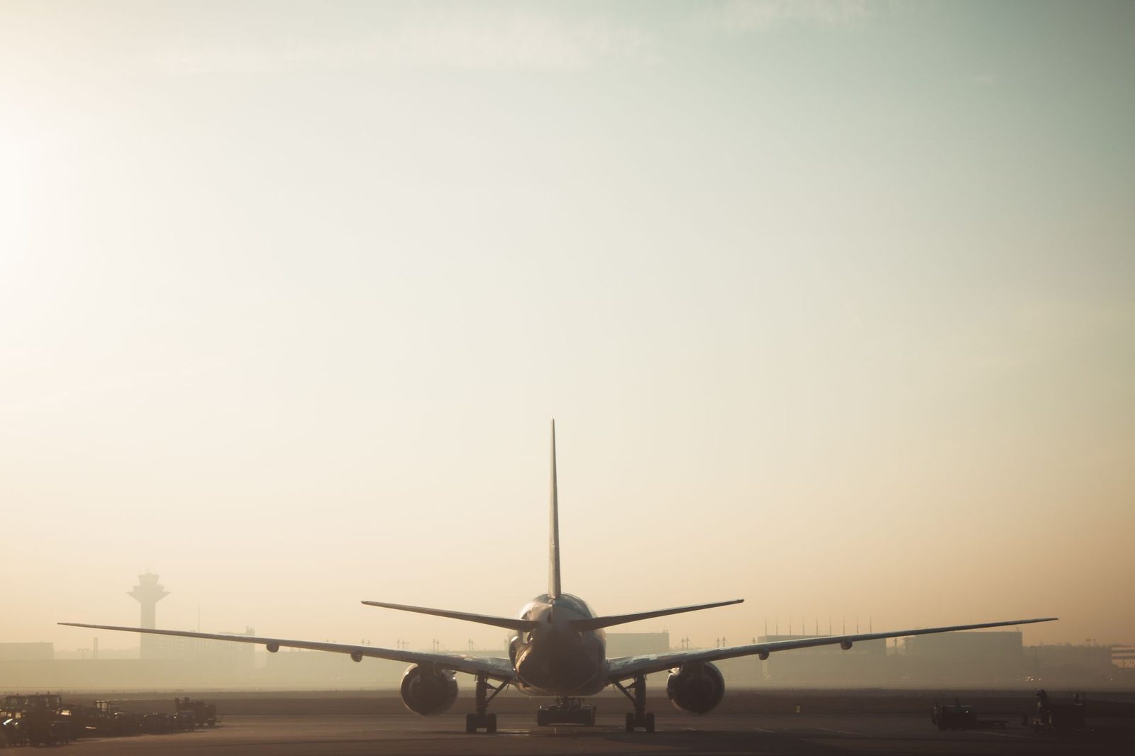 Avion de ligne vu de face sur le tarmac d'un aéroport au lever du soleil, tour de contrôle en arrière-plan