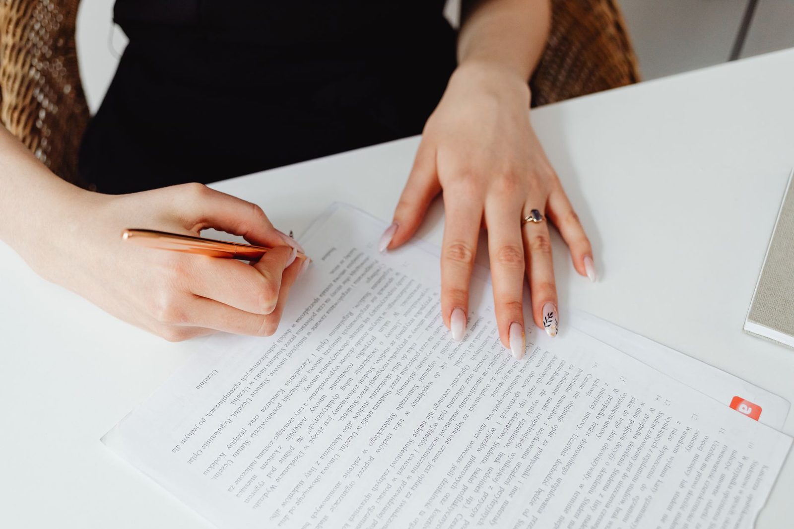 Jeune femme signant un document imprimé avec un stylo, posé sur un bureau blanc