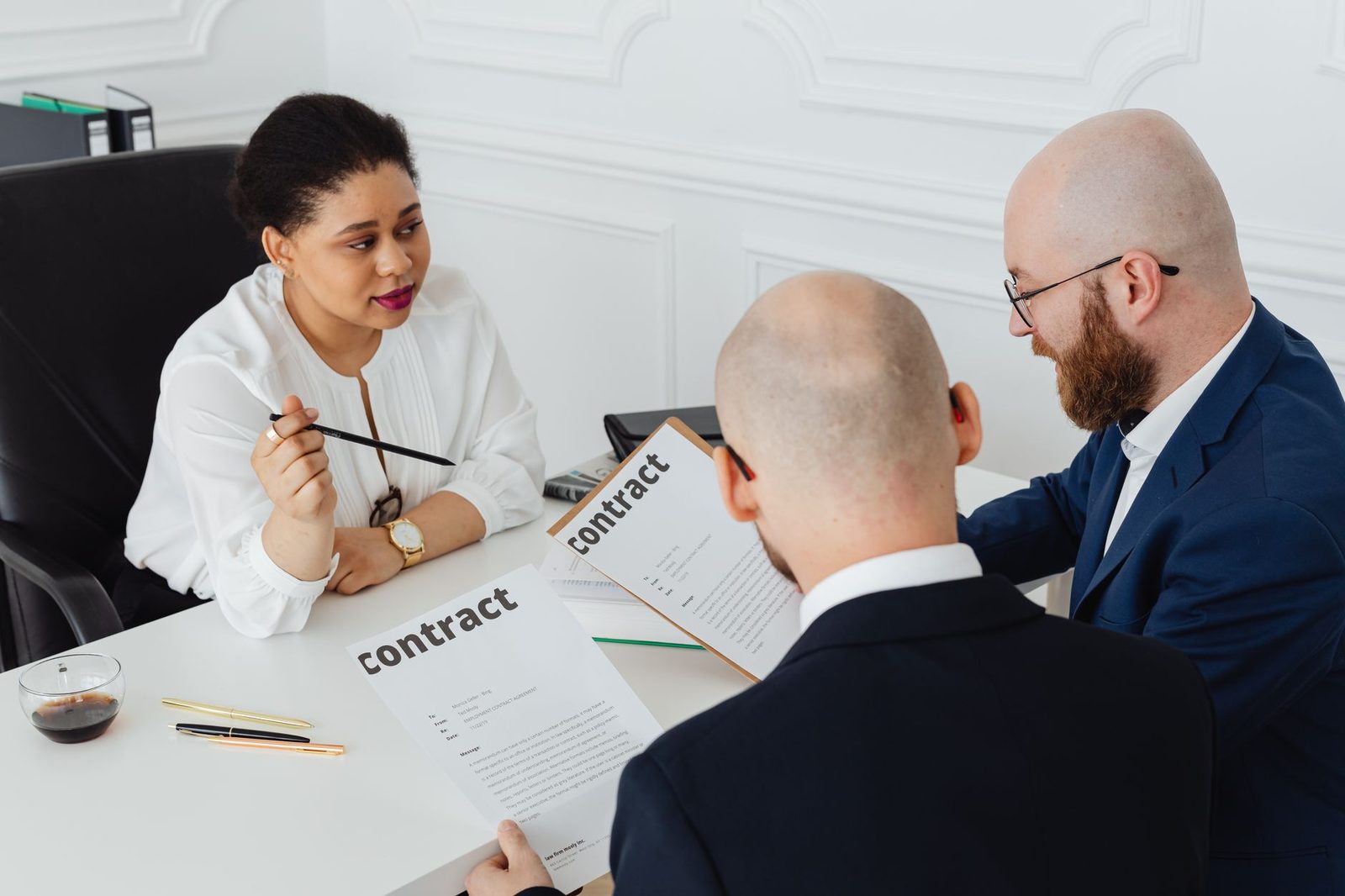 Trois personnes autour d'une table de bureau examinant des documents intitulés « contract »