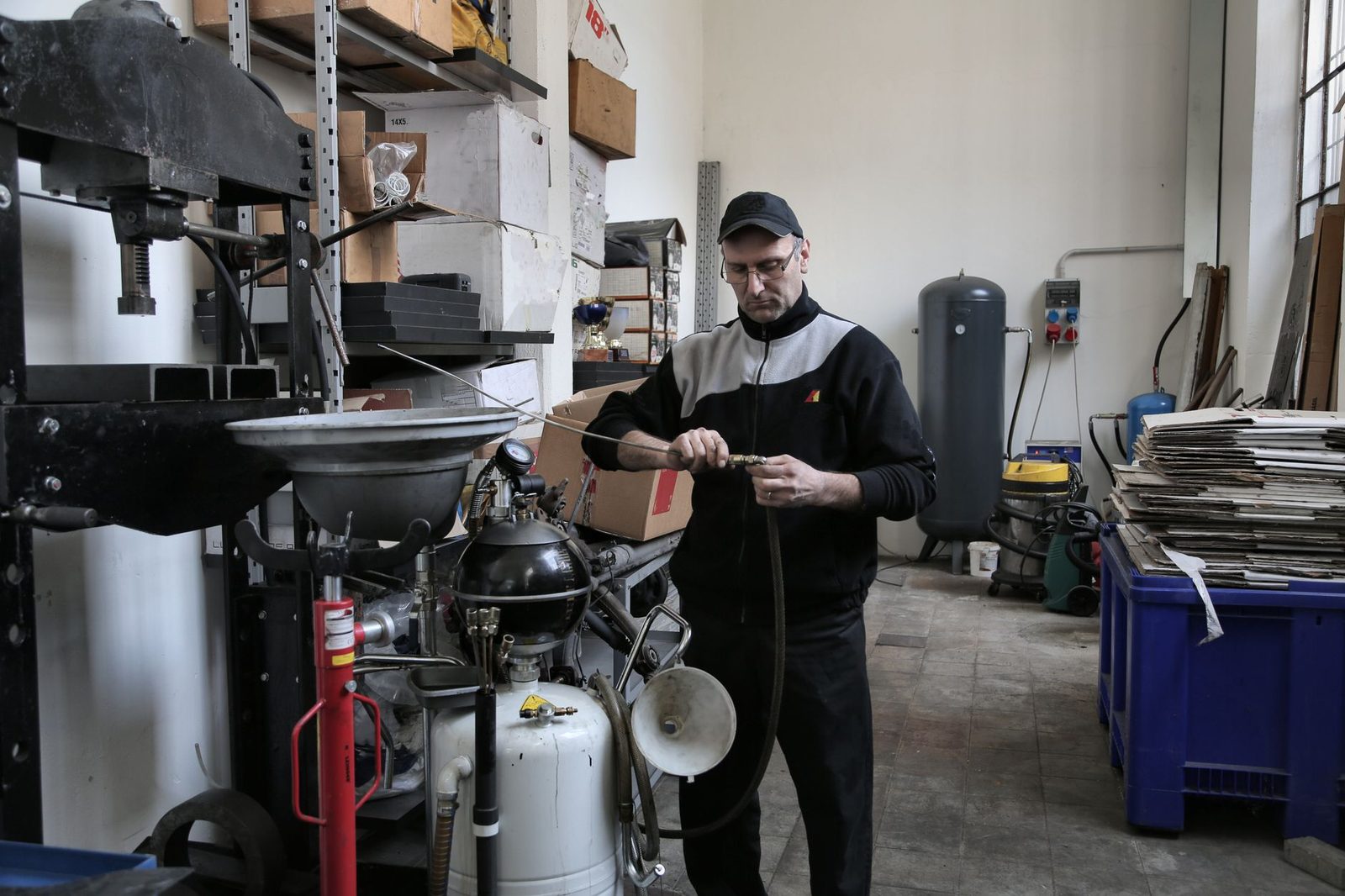 Homme en casquette manipulant un tuyau près d'équipements dans un atelier d'artisan
