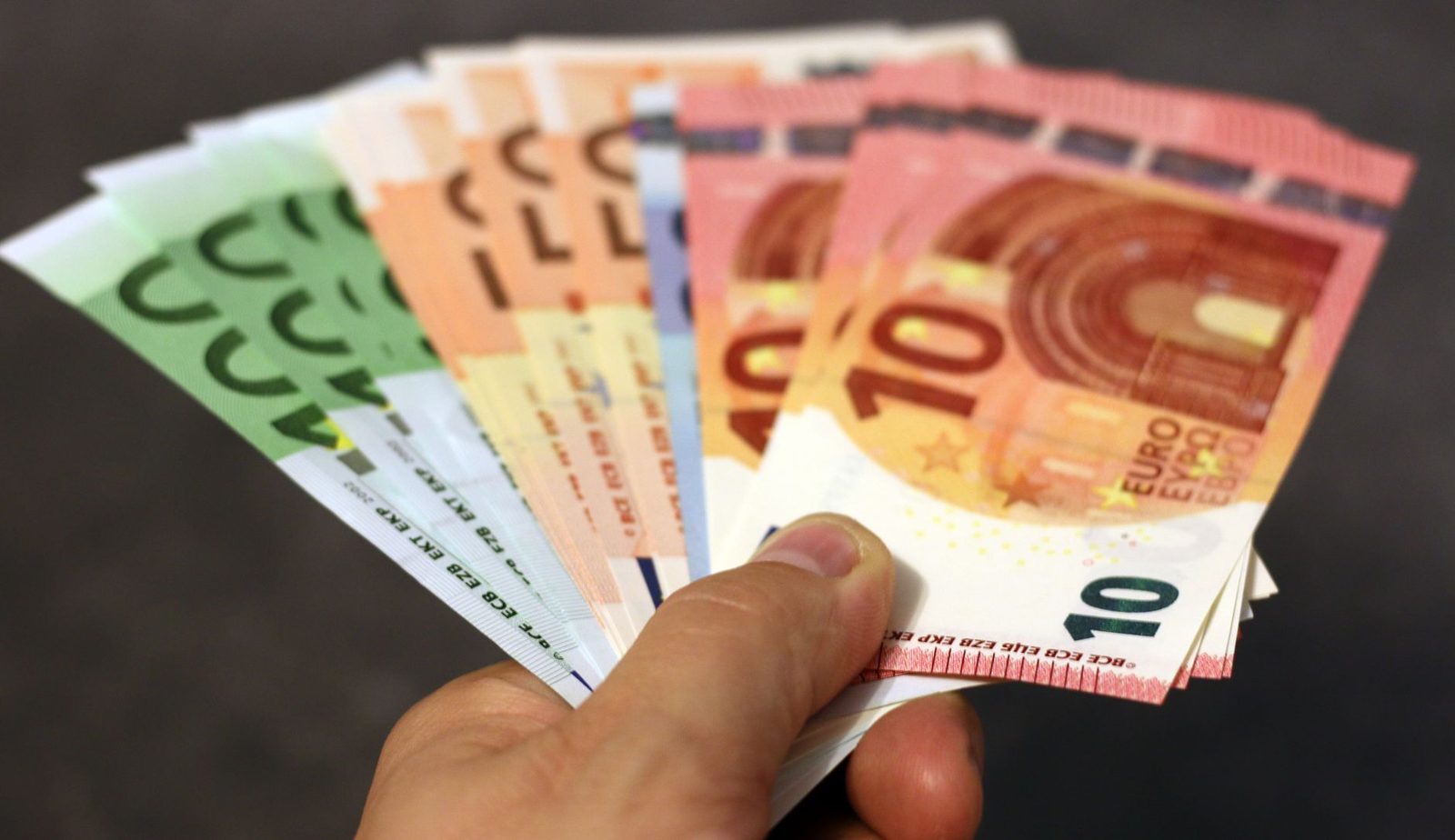 Main tenant en éventail plusieurs billets en euros de 10, 20, 50 et 100 euros