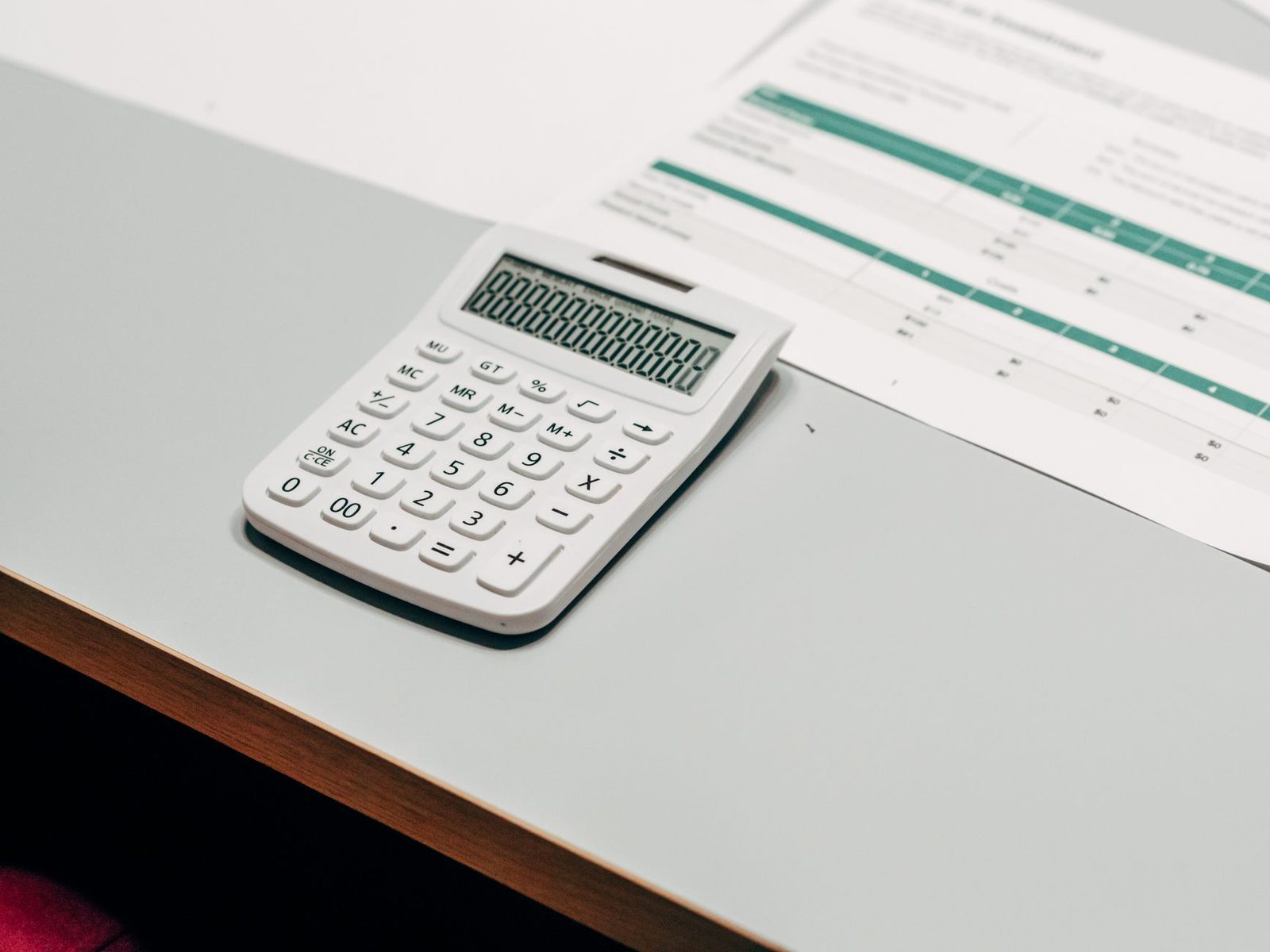 Calculatrice blanche posée sur un bureau à côté d'un document imprimé avec un tableau chiffré