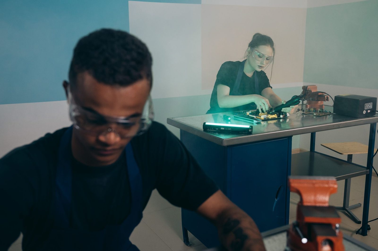 Deux jeunes en tablier et lunettes de protection travaillent sur des circuits électroniques dans un atelier de formation