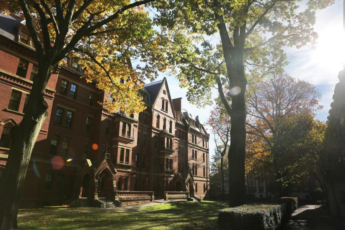 Bâtiments en brique rouge d'un campus, entourés d'arbres aux feuilles d'automne