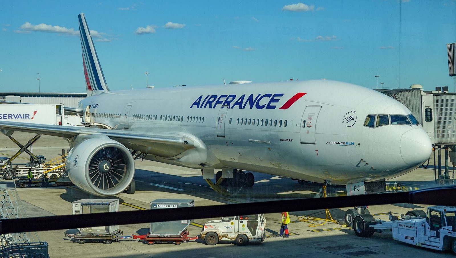 Avion Boeing 777 d'Air France stationné à la porte d'embarquement avec véhicules de piste au sol