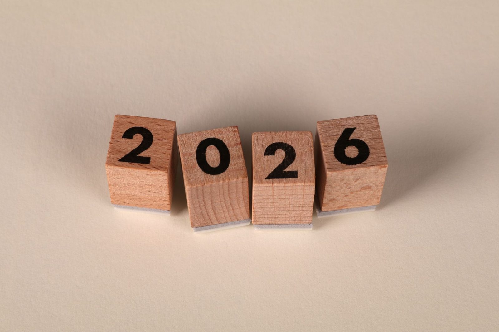 Quatre cubes en bois alignés affichant le nombre 2026 sur un fond neutre.