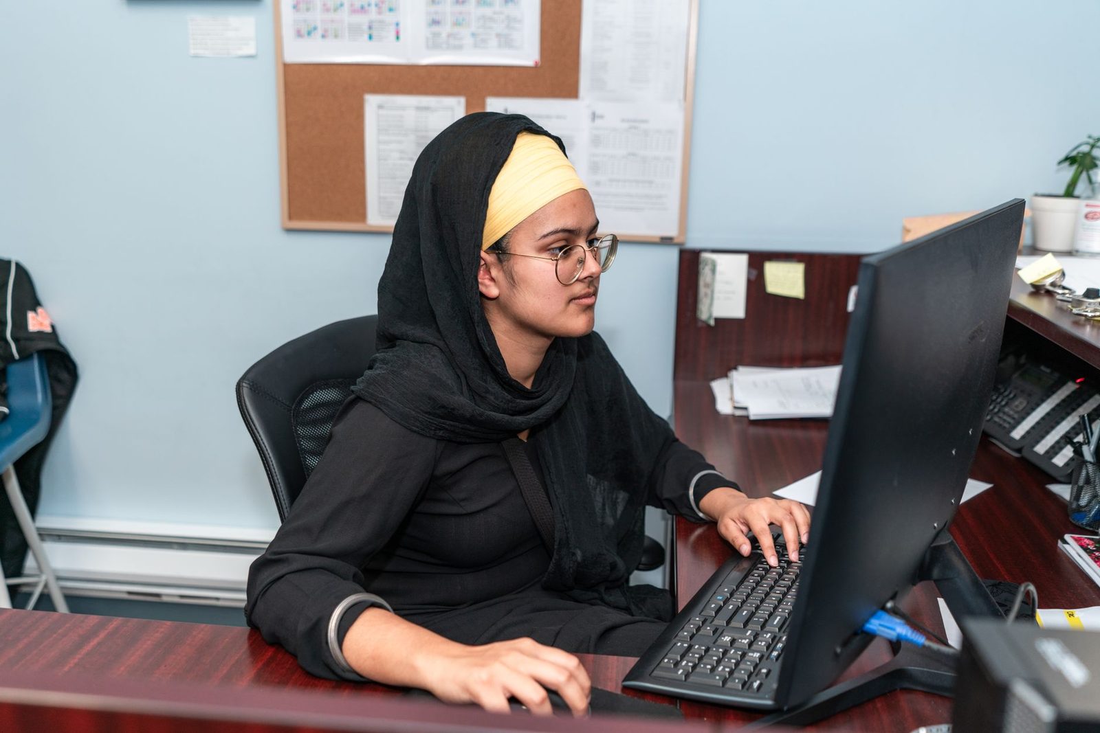 Jeune femme portant un voile noir travaillant sur un ordinateur à un bureau dans un bureau