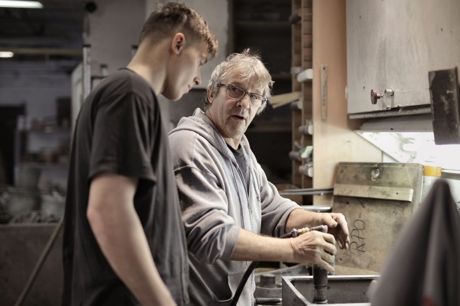 Un artisan expérimenté explique l'utilisation d'un outil à un jeune apprenti dans un atelier