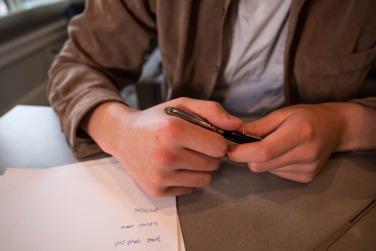 Un jeune alternant assis à son bureau, calculatrice et bulletin de paie en main, vérifie le montant de son salaire mensuel