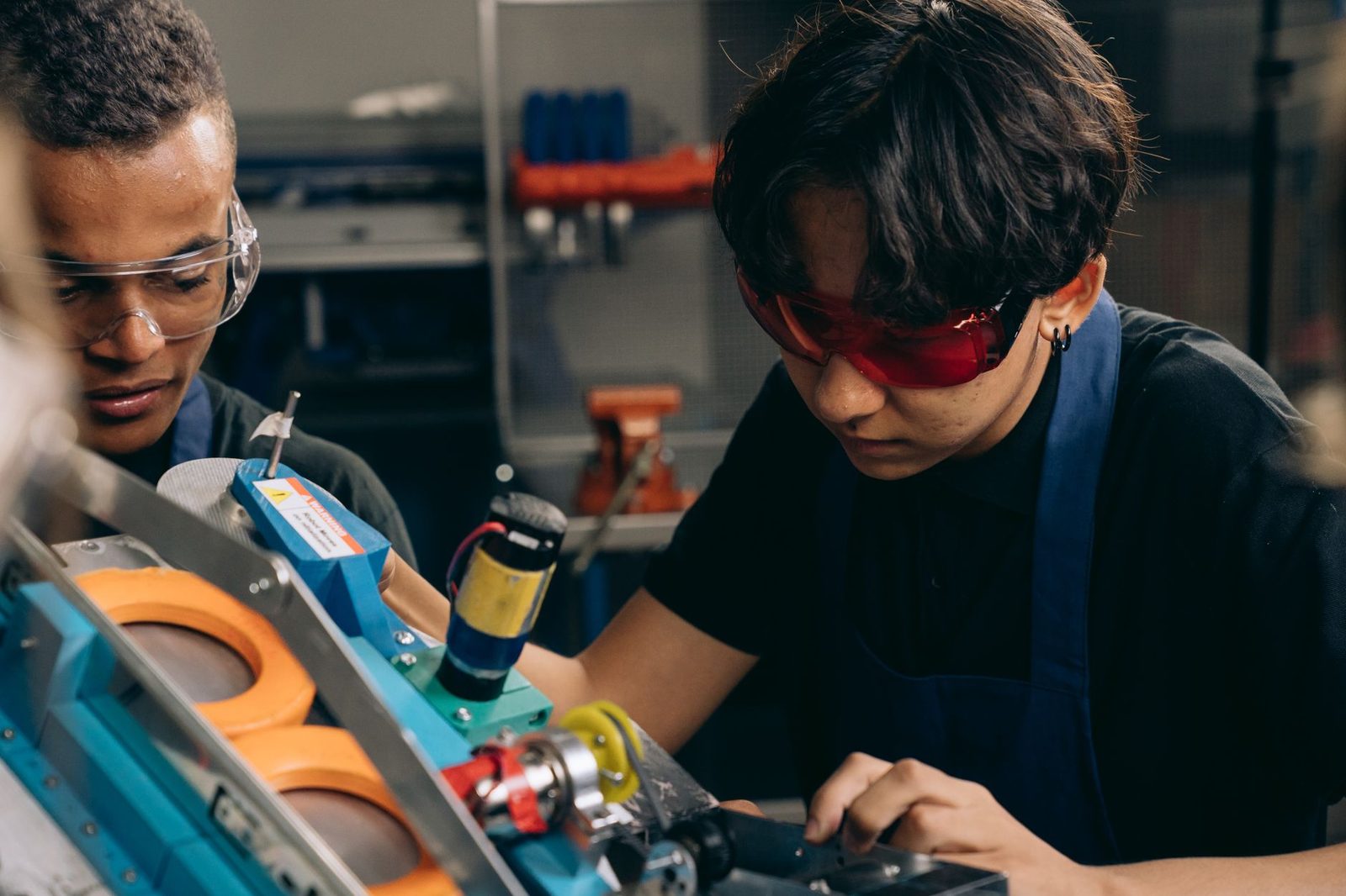 Deux jeunes en lunettes de protection manipulent une machine dans un atelier de formation