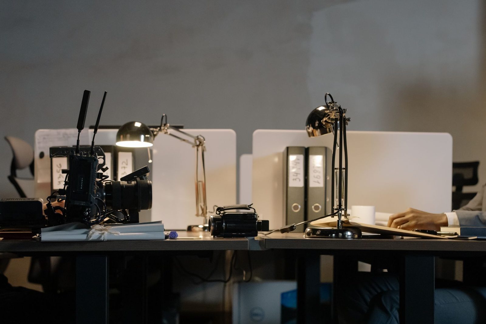 Bureaux en open space avec lampes allumées, classeurs et une personne travaillant au fond