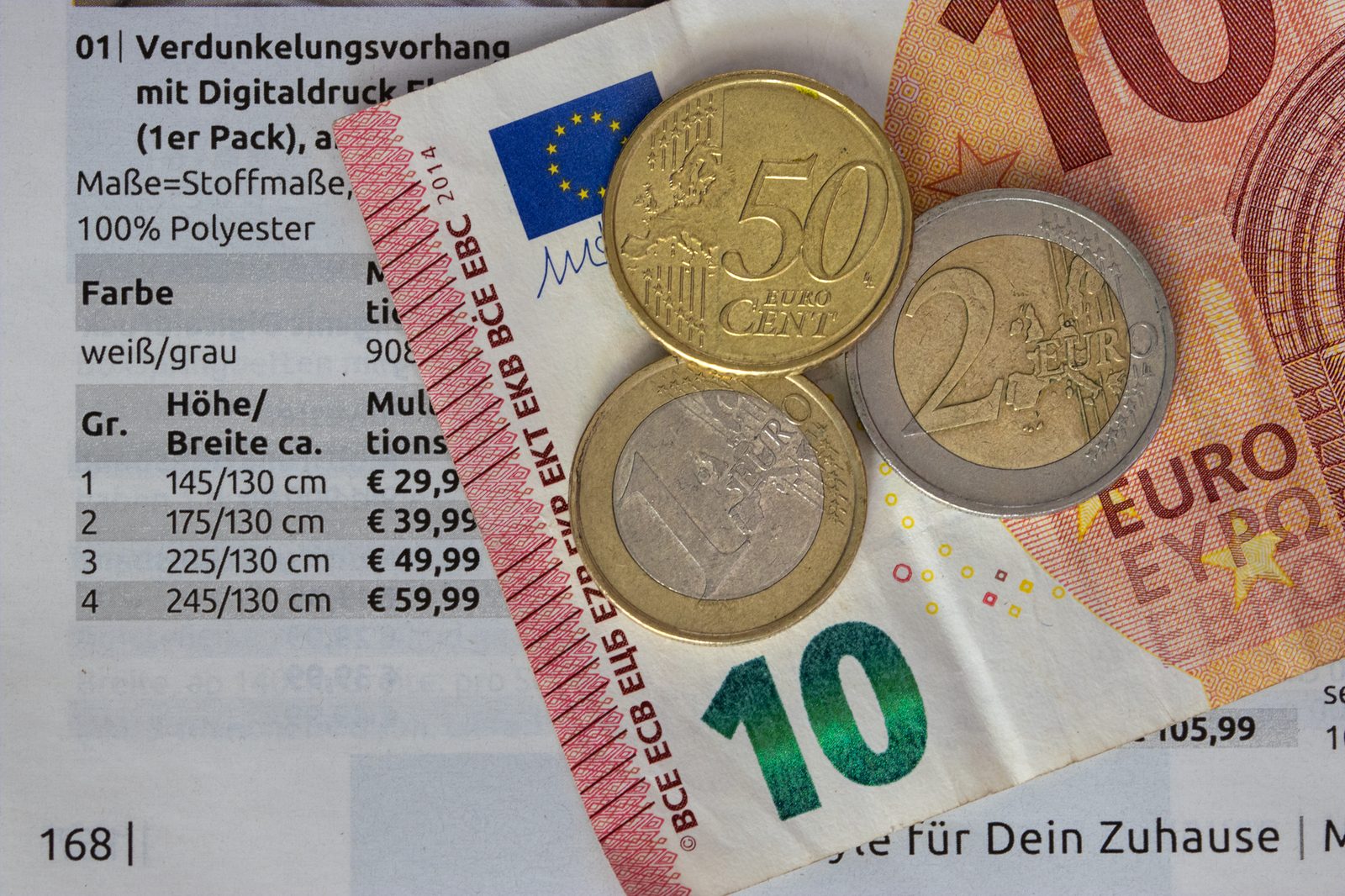 Pièces en euros et billet de 10 euros posés sur une page de catalogue avec des prix