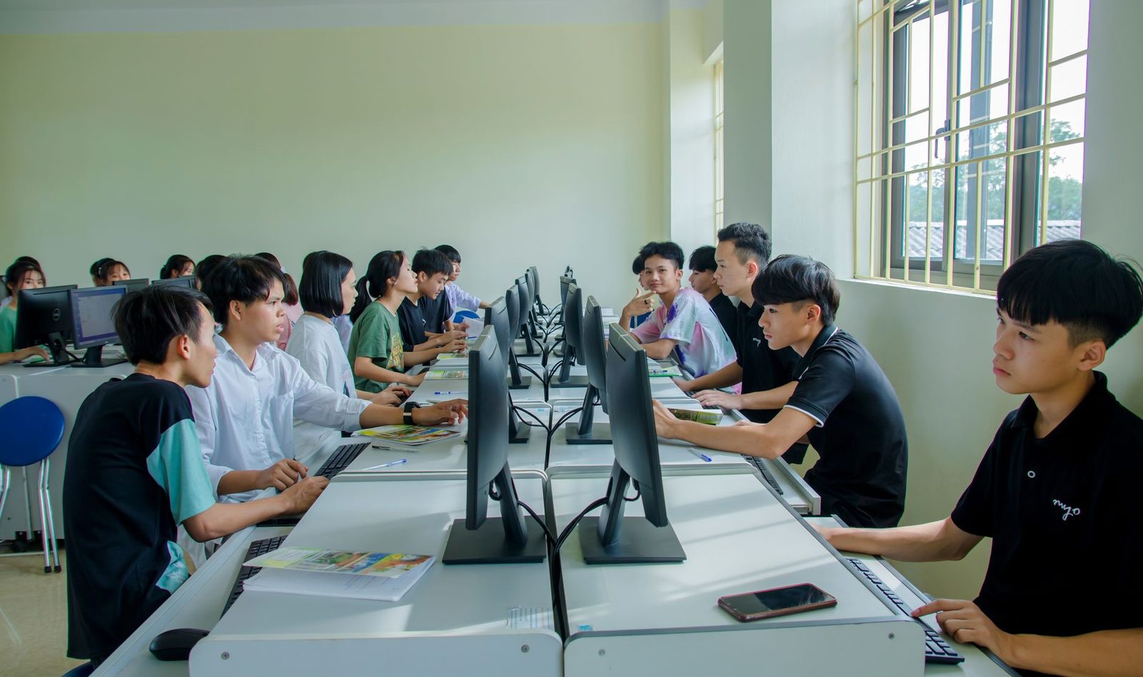 Jeunes étudiants assis devant des ordinateurs dans une salle informatique de formation